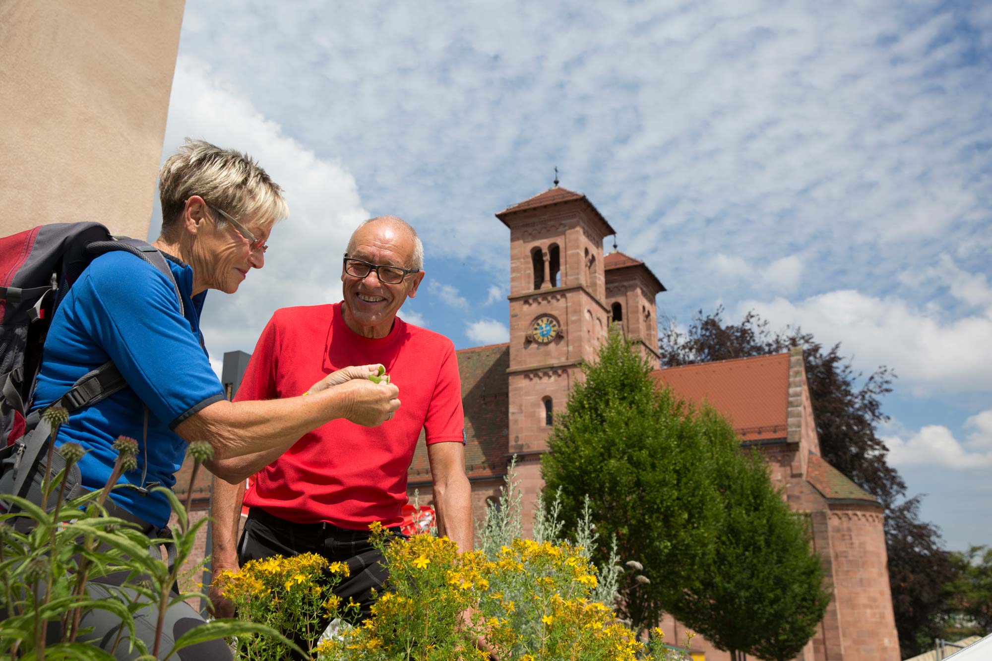 Mann und Frau am Kräuterbeet mit Kirche